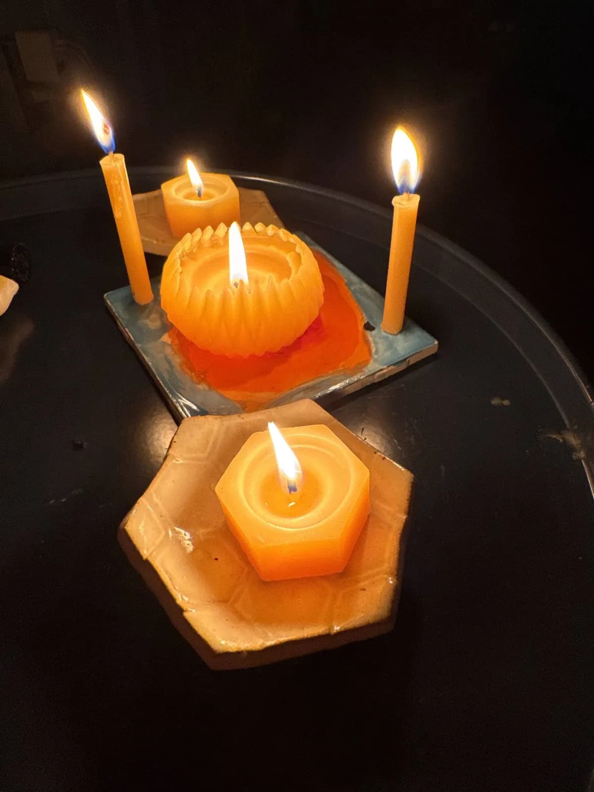 Beeswax candles glowing in hand-made ceramic dishes at night